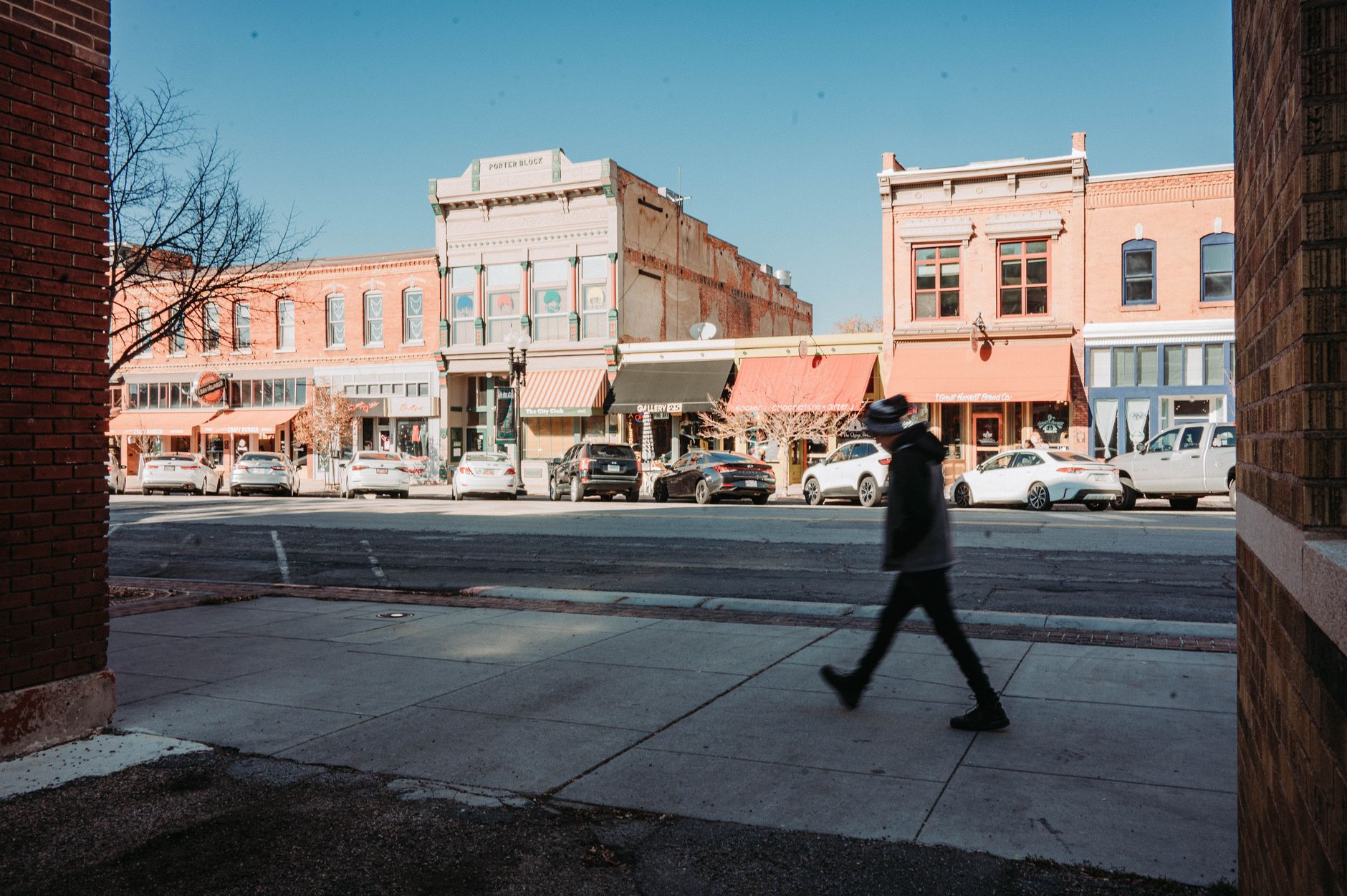 A pedestrian walks past historic buildings on an urban street.
