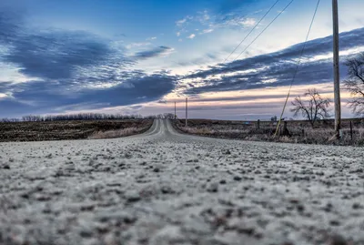 A deserted rural road stretches into the horizon under a dramatic sunset sky in Minnesota.
