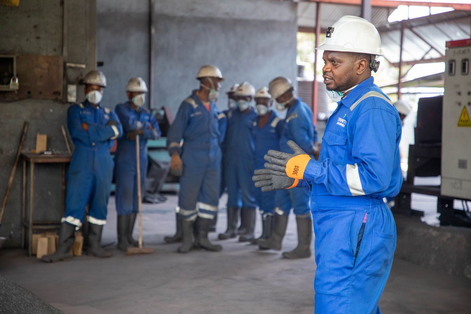 A group of factory workers in safety gear receiving training indoors.