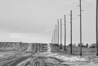 A black and white photo of a snowy rural road with utility poles in Minnesota.